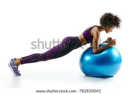 Sporty girl doing plank exercise on gymnastic ball. Photo of sporty african girl in sportswear on white background. Sports