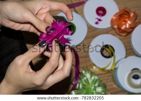 Female hands making a ribbon on wooden floor, For decorate a gift on wooden background