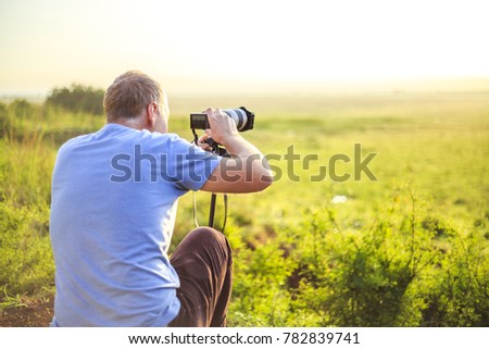 Professional photographer taking photo on savannah at sunrise