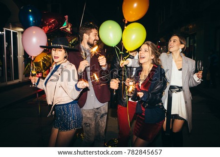 Group of happy friends going on the party, having fun at the street and drinking champagne. New year party. Birthday party