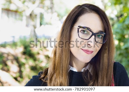 Portrait of a mature woman wearing eyeglasses, front view, outdoors, sweet smile.