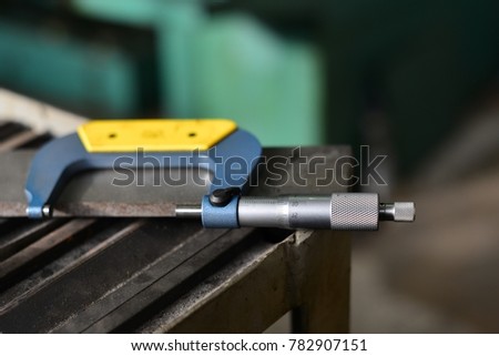 Elderly worker looks in the drawing to see detail sizes. The man turner measures the dimensions of the part on a micrometer, and also uses a sliding caliper.