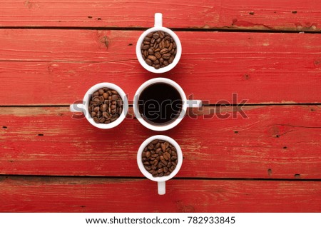 Coffee cups and coffee beans on red wooden background. Coffee.