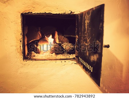 Warm light of a burning bright fire in a fireplace in old Russian stove. Flame and firewood background. Detail of interior.