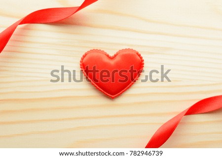 From above small fabric heart and ribbons on wooden background.
