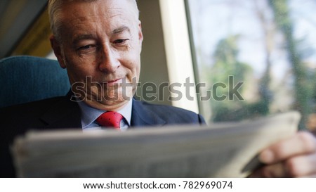 Mature business investor reading a newspaper during a train journey Royalty-Free Stock Photo #782969074