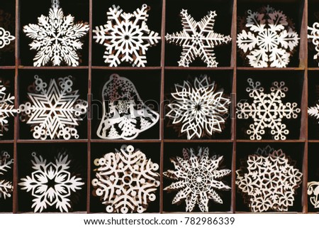 Rack at the Christmas Fair is filled with wooden hand-made white snowflakes and bells with carved patterns.