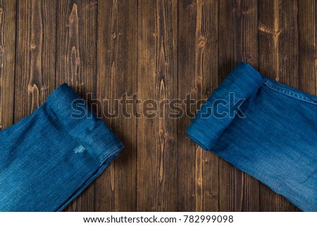 Roll Frayed jeans or blue jeans denim collection on rough dark wooden table background with copy space, old fashion style concept.