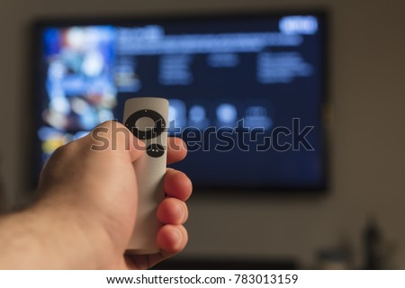 Holding hand on remote control Royalty-Free Stock Photo #783013159