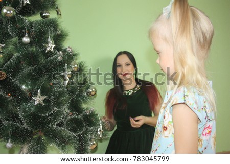 Christmas and a child with blond hair. child with funny tails on his head. hanging toys. Mom in the background is smiling. photo for your design.