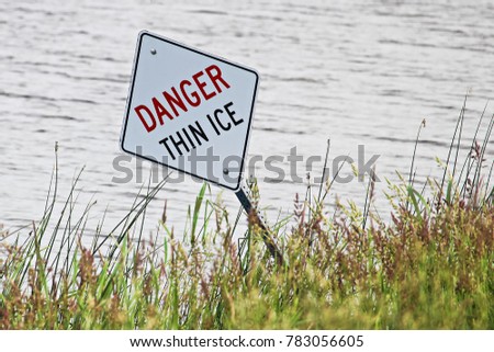 A danger thin ice sign along the shore in summer.