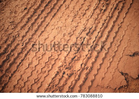 Traces from the car on the red clay soil after raining.