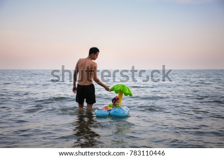 Having fun and joy concept. Focus at cute little baby girl with her dad are playing in the sea. Playful active kid on beach in summer vacation.