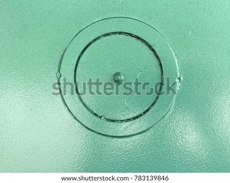 The abstract art design of big circle with small screw at the middle of grunge surface steel platy with acrylic green color spray,