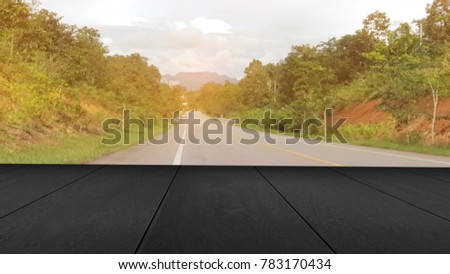wooden board with blurred image of road in the countryside has tree along the way