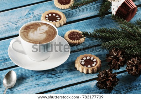 Cappuccino on the new year background - fir tree, cones, cookies on a blue wooden background