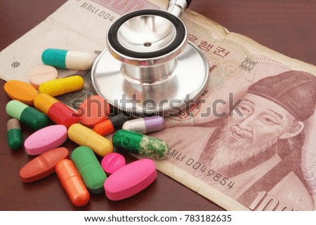 Stethoscope, many drugs ans korean money on table, price of medical help concept