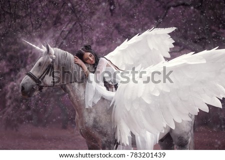 Beautiful, young elf, walking with a unicorn. She is wearing an incredible light, white dress. The girl lies on the horse. Sleeping Beauty. Artistic Photography Royalty-Free Stock Photo #783201439