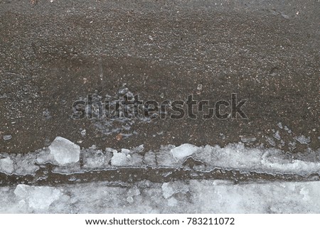 a puddle in which water drips on the asphalt and snow
