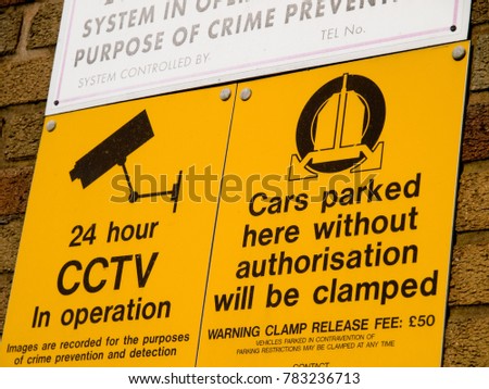 Security sign on a wall warning of clamping if parking is unauthorised
