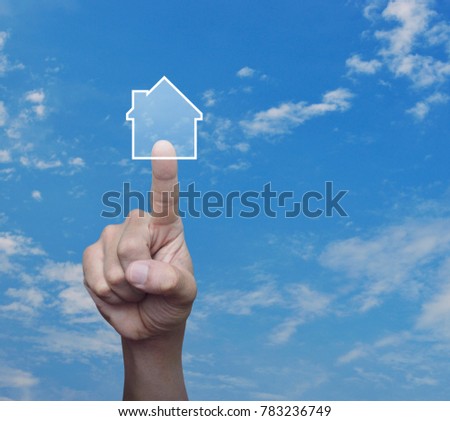 Hand pressing house icon with copy space over blue sky with white clouds, Real estate concept