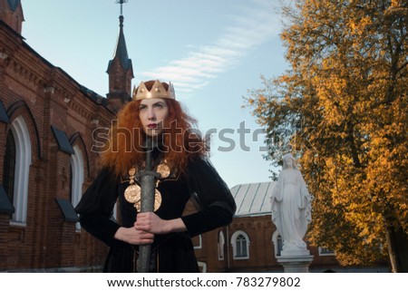Medieval Queen with a sword in her hand on a church background