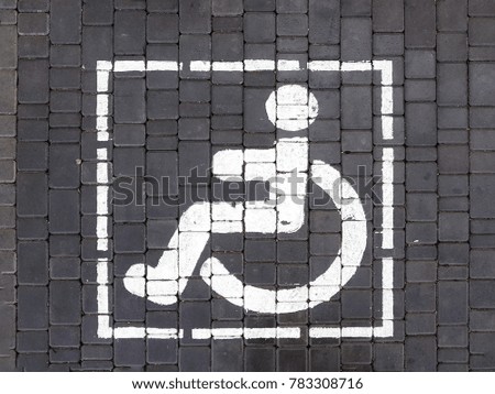 symbol handicapped painted on the road, a parking sign for the disabled on the paving slab.