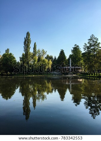 Park lake with trees reflecting in the water, Pitesti, Romania Royalty-Free Stock Photo #783342553
