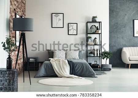 Vase on metal table and grey lamp in spacious bedroom with white carpet and gallery on wall above bed Royalty-Free Stock Photo #783358234