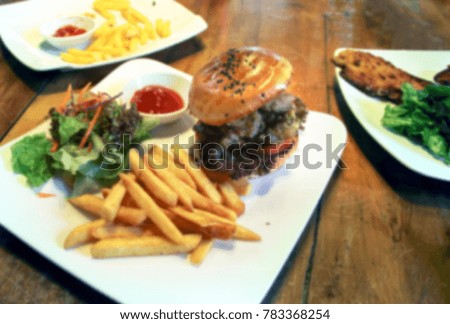 Blur image of burger and french fries fast foods on wooden table
