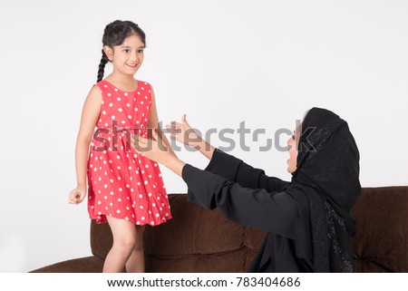 Arab woman playing with her daughter at home with white background