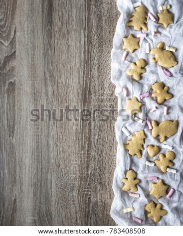 a wooden table, and on the right are laid out on white cloth gingerbread cakes as a tree of hearts of hares of little teddy bears and stars, marshmallows lay