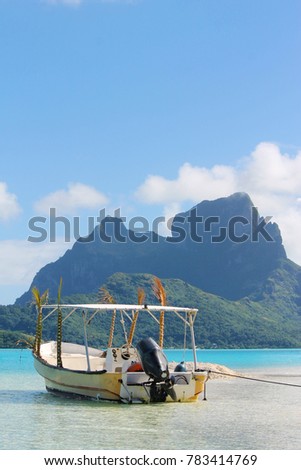 Vertical photo of a dream landscape: motor boat on a sandy beach in Bora Bora with the background mountains, French Polynesia