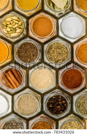 Colorful herbs and spices in hexagonal glass jars. Natural colors and top view. Vertical picture.