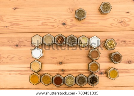 Colorful spices surround space for text. A few herb jars are spread out around the frame. Horizontal picture.