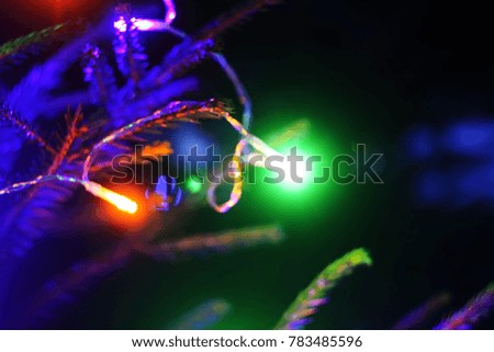 Festive New Year background with blurred colorful lights on decorated fir tree branches outdoors.