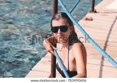 Girl sitting on the pier wearing sunglasses