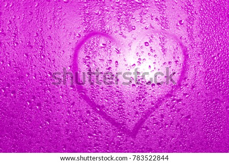 a symbol of the heart and love is drawn on a wet misted glass in the sun. Using a selective focus