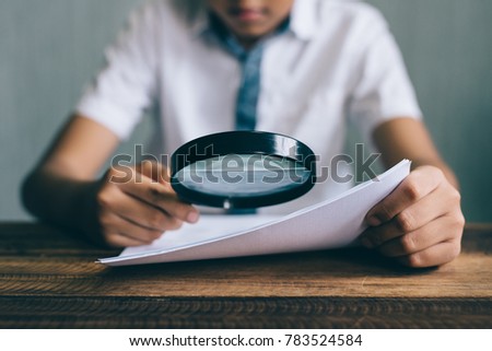 asian boy student looking at paper using magnifying glass. education concept Royalty-Free Stock Photo #783524584
