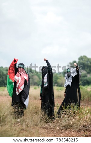 Three female Muslim  wearing black abaya and keffiyeh to cover their faces and mafla with Arabic words mean "We are the frontliners" and "Brigade AlQassam", military wing of the Palestinian Hamas