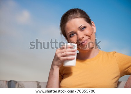 Young relaxing woman with coffee cup. Blue sky background.