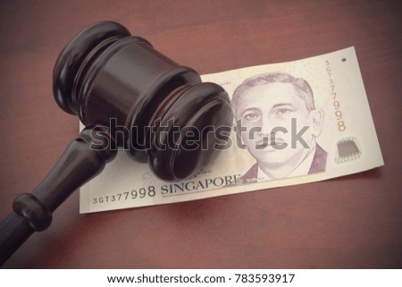 Singapore money and judge's gavel on brown wooden table, finance and law concept