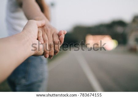 Select focus and soft focus. Lovers walk hand in hand in the park road after sunset to follow the lights of the restaurant around the garden.Couples who hold hands To encourage each other.