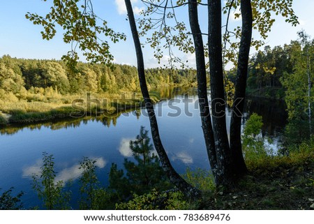 high water level in river Gauja, near Valmiera city in Latvia. summer trees surrounding and reflections of white clouds