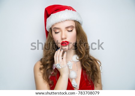 Beauty face close-up photo portrait. Beautiful girl wearing Christmas red hat cap. Pretty woman stylish make up, glossy lips, happy New Year party. Santa girl, dreaming think about presents, surprises