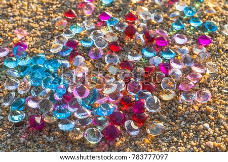 sunshine on the beach in the morning light through gemstones are falling scattered about on the beach.