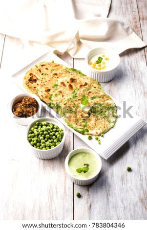 Green Peas Stuffed Flat Bread or Matar ka Paratha is a traditional food from North India. served with mango pickle, over moody background, selective focus