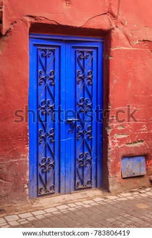 Old house with a red wall and a blue ornated door in the old town of Marrakesh called Medina