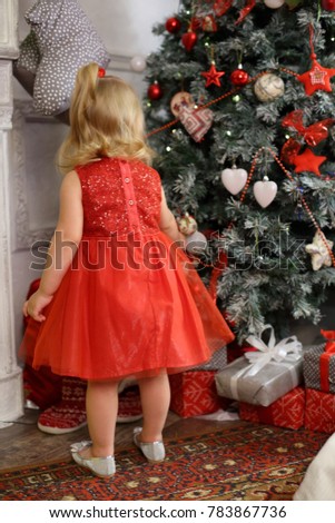 little girl in the red dress near the Christmas tree