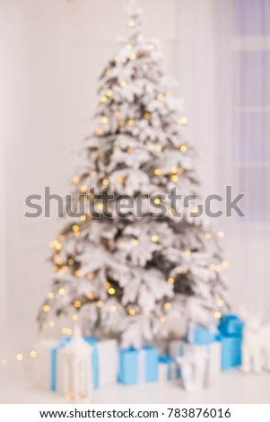 Blurred beautiful glowing Christmas tree and many gift boxes under it in holiday home interior. Vertical color photography.